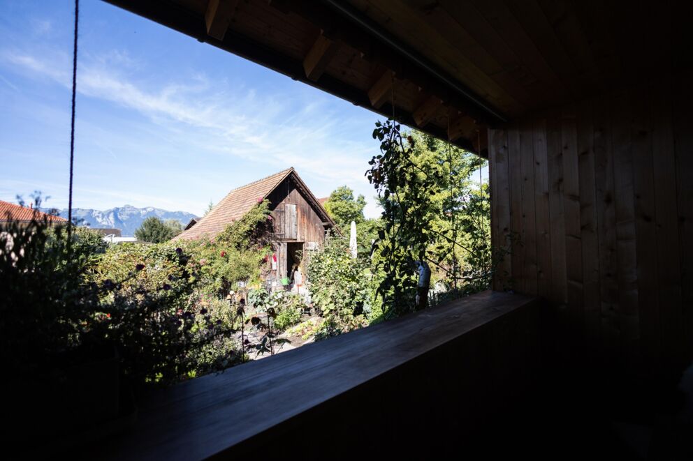 View of an idyllic garden with old wooden houses and mountain panorama.