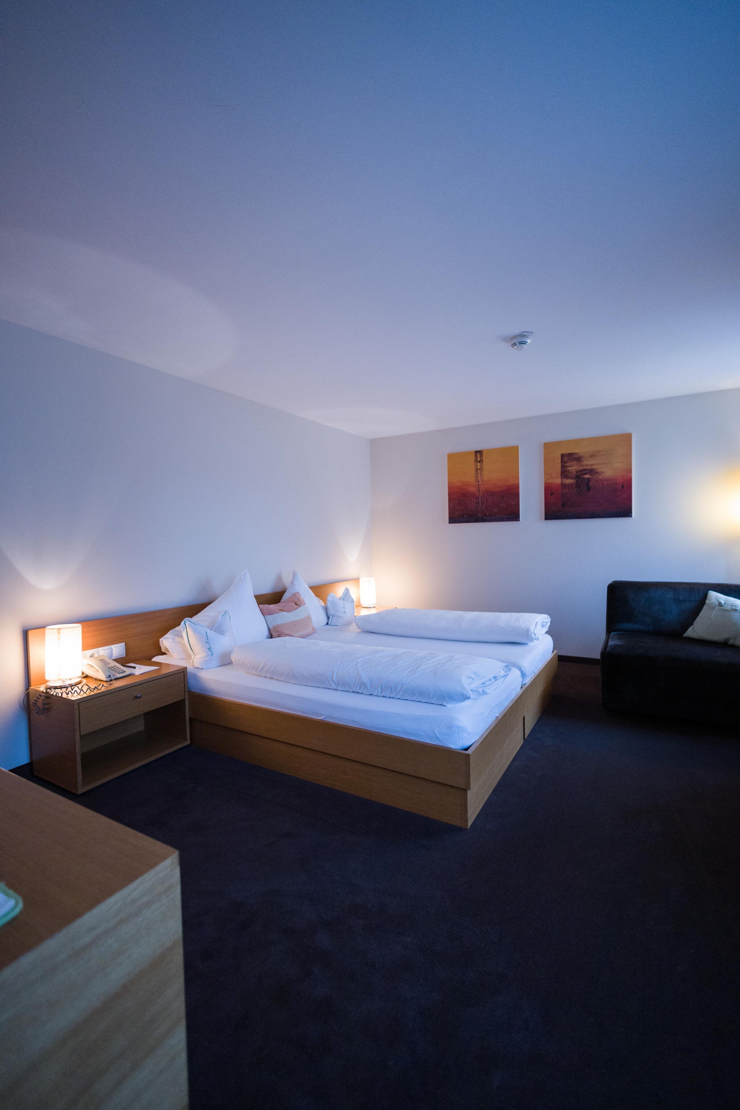 Bright double room with wooden furniture, cozy cushions and soft lighting.