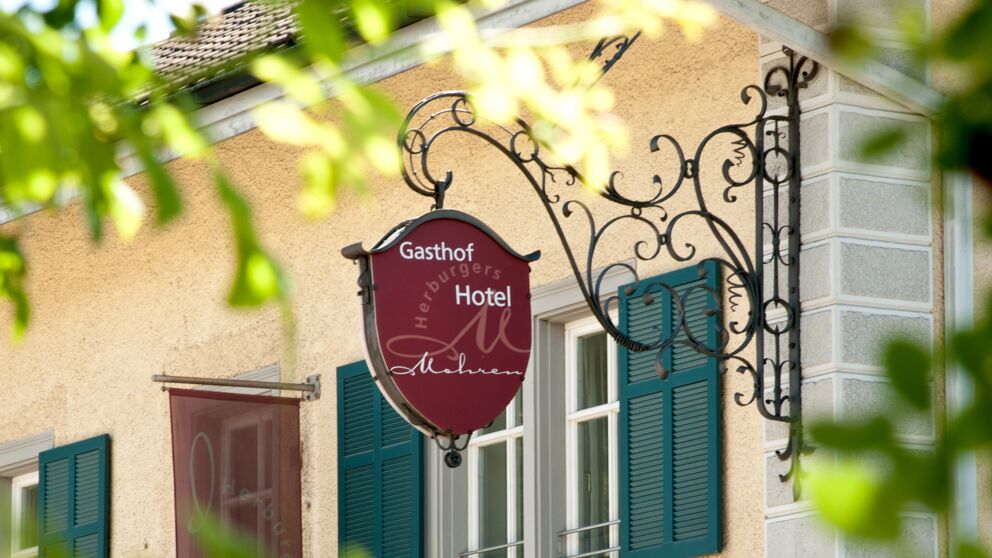 Schild des Gasthofs Mohren mit dekorativem Schmiedeeisen und grünen Fensterläden.