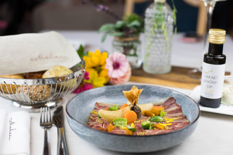 Elegantly prepared dish with fresh ingredients, flowers and regional dip.