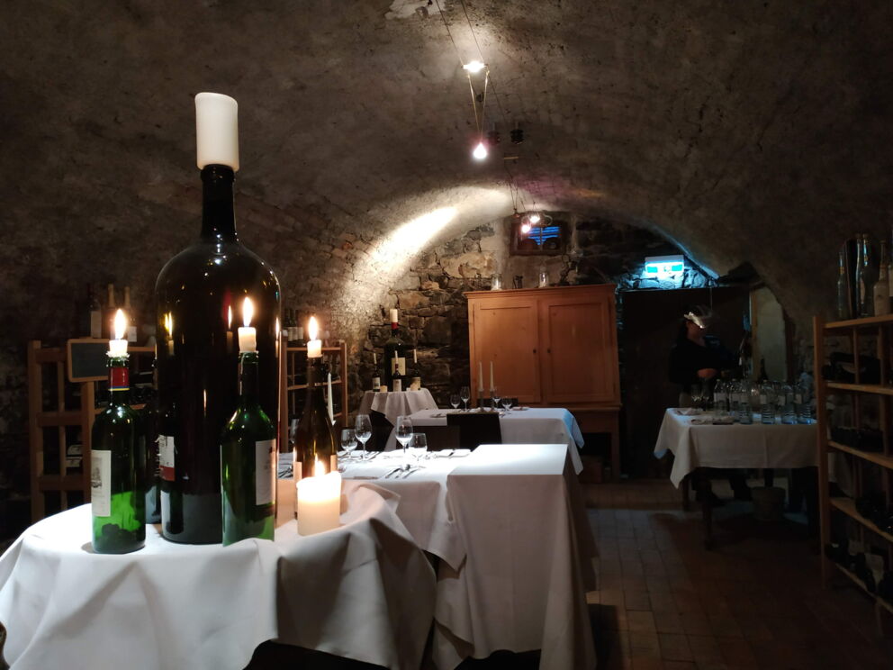 Atmospheric candles in the rustic wine cellar with covered tables and stone walls.