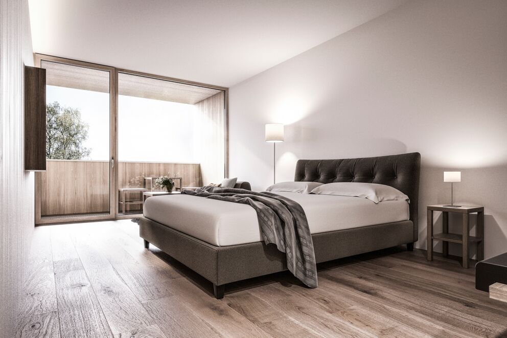 Bright bedroom with modern bed, lamps and wooden floor, exit to the balcony.