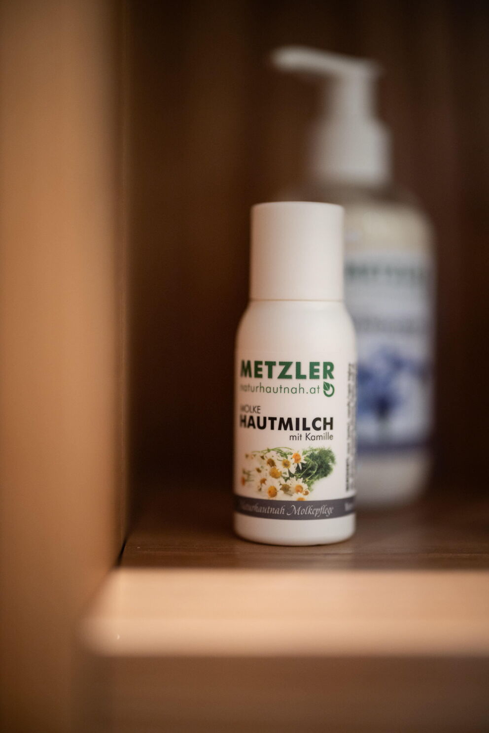 Bottle of whey skin milk with camomile on a wooden shelf in the bathroom.