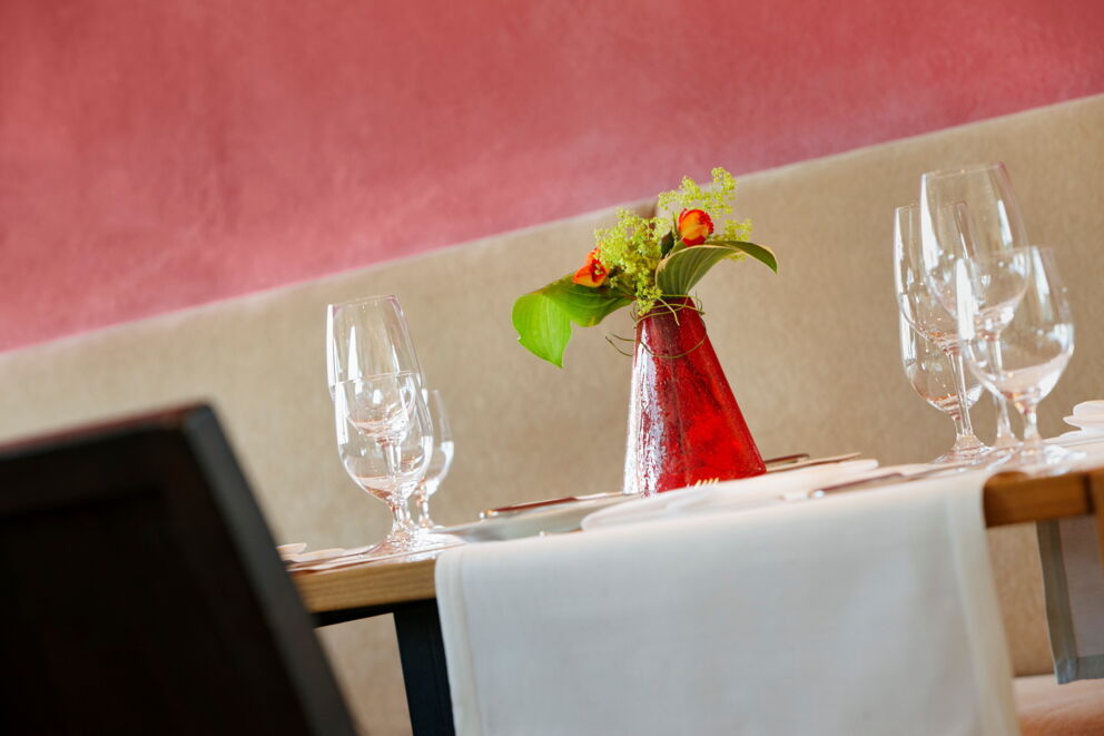 Table with red vases, flowers and elegant wine glasses in the restaurant.