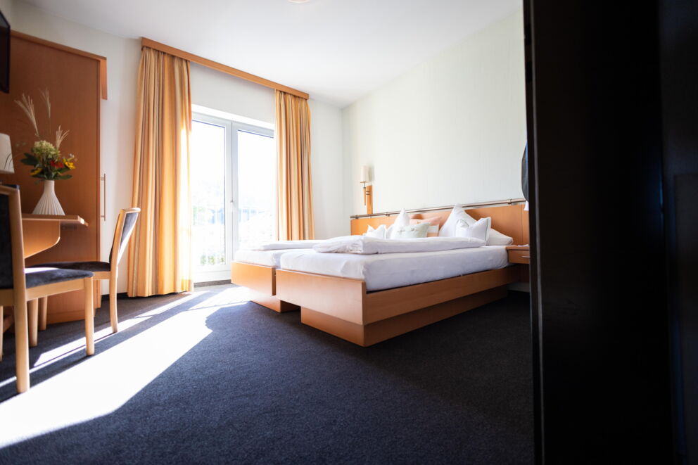 Helles Zimmer mit großen Fenstern und eleganten Vorhängen in warmen Tönen.