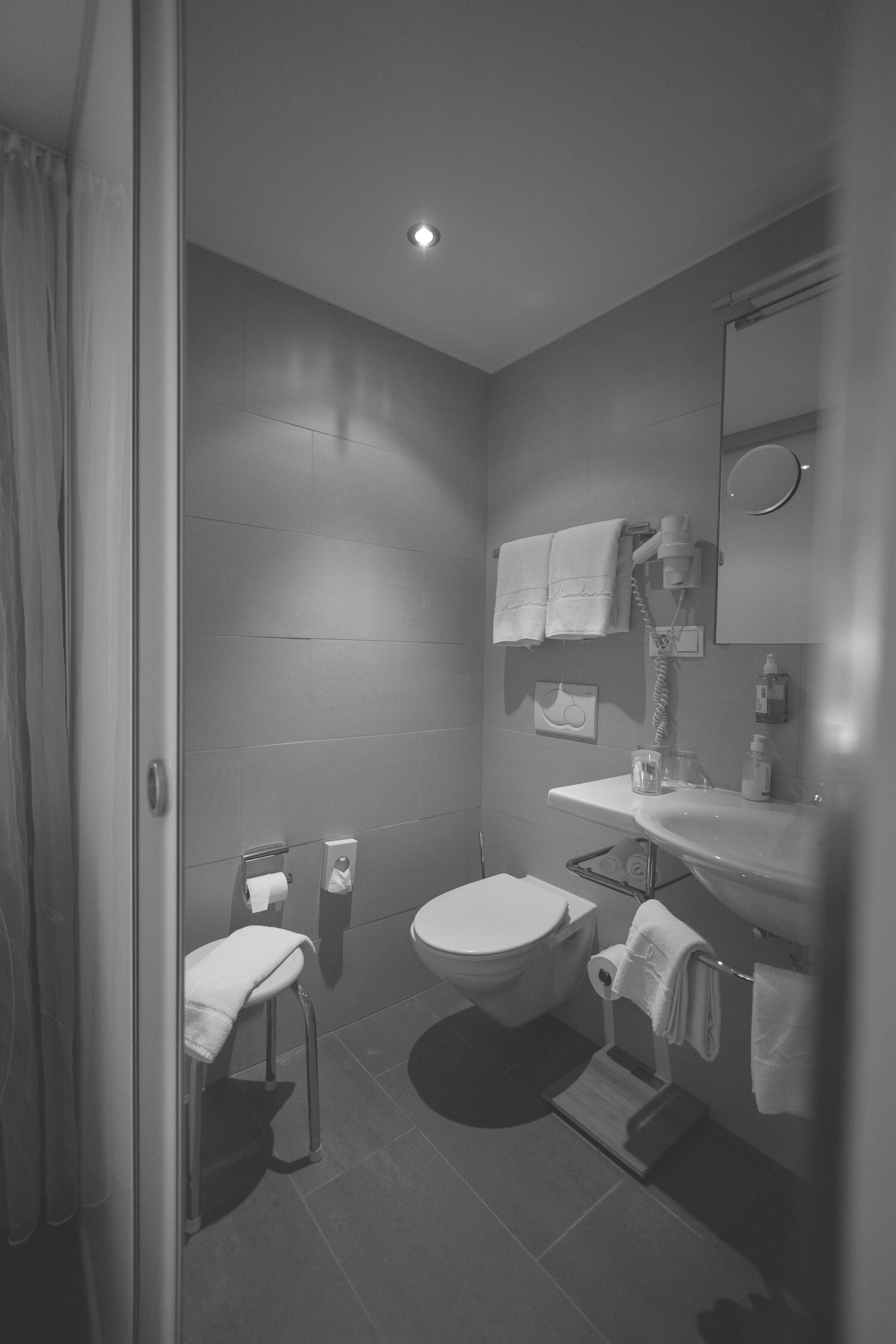 Elegantes Badezimmer mit Handtüchern, WC, Waschbecken und dezenter Beleuchtung.