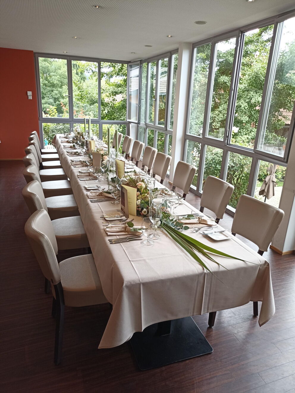 Long, elegantly laid table with a view of green trees in a bright room.