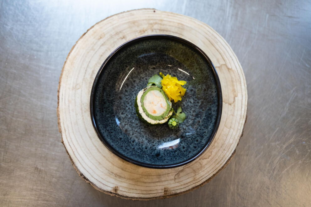 Artfully arranged dish presented in a black bowl on a wooden disk.