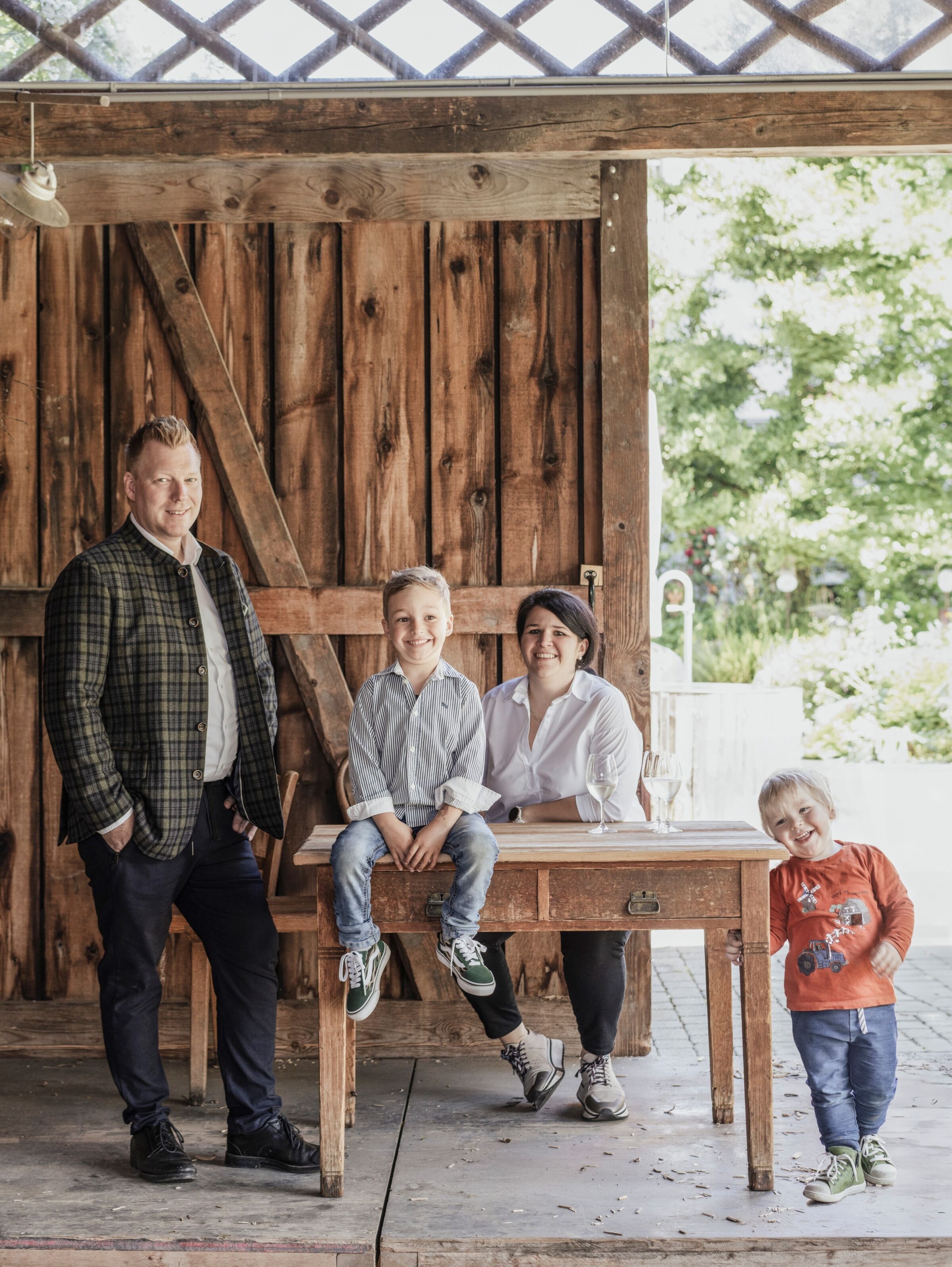 Smiling family sitting at a rustic wooden table in the sunny garden