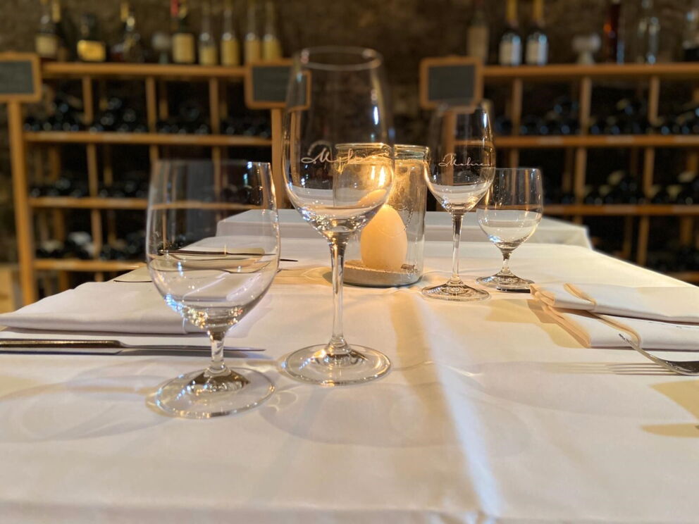 Set table with wine glasses and candle in a cozy wine cellar.