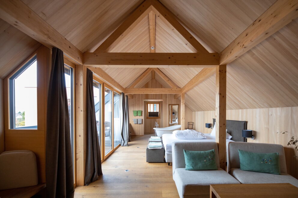 Helles Zimmer mit Holzwänden, großen Fenstern und gemütlichen Sitzgelegenheiten