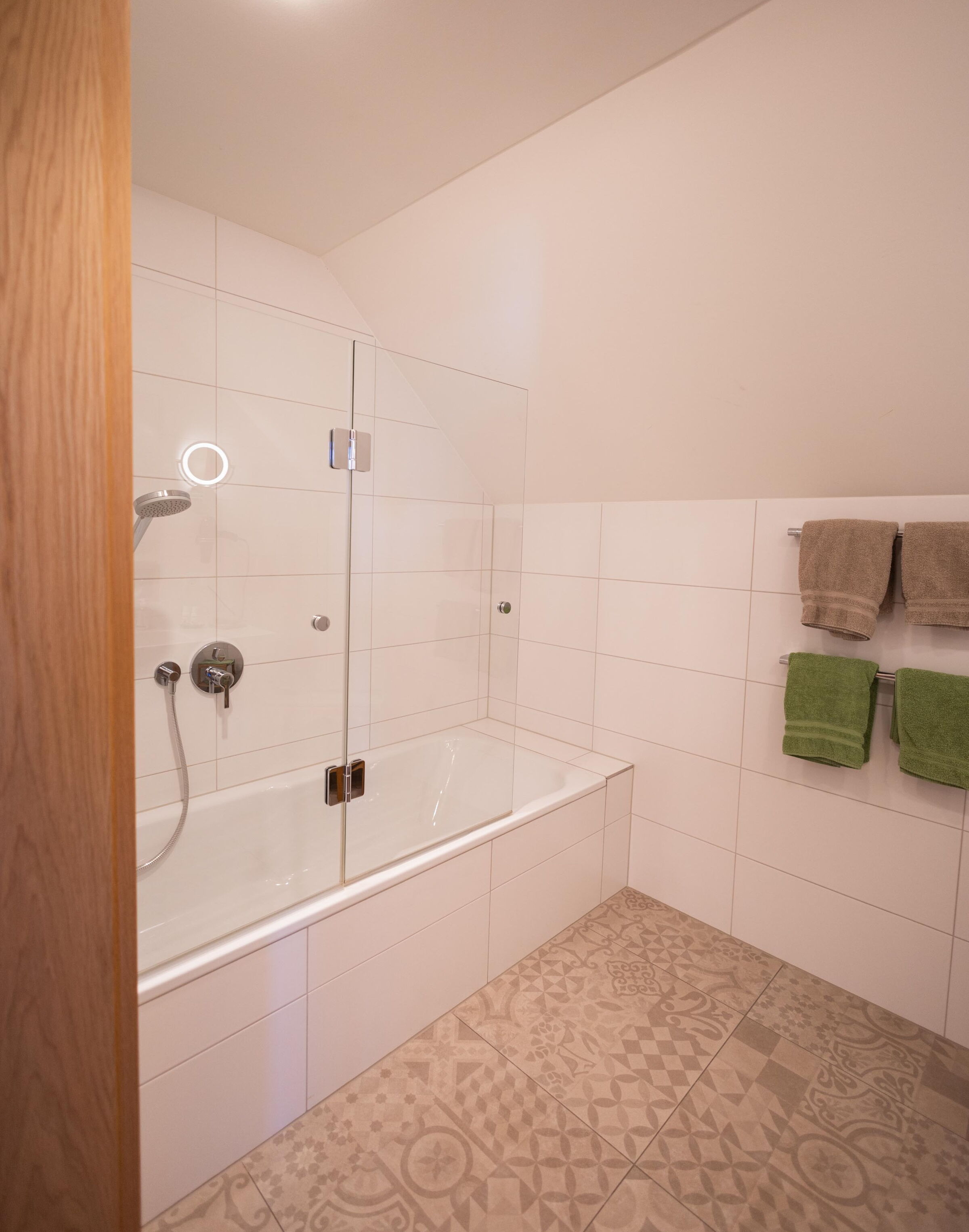 Bright bathroom with bathtub, glass partition and hand-picked towels.