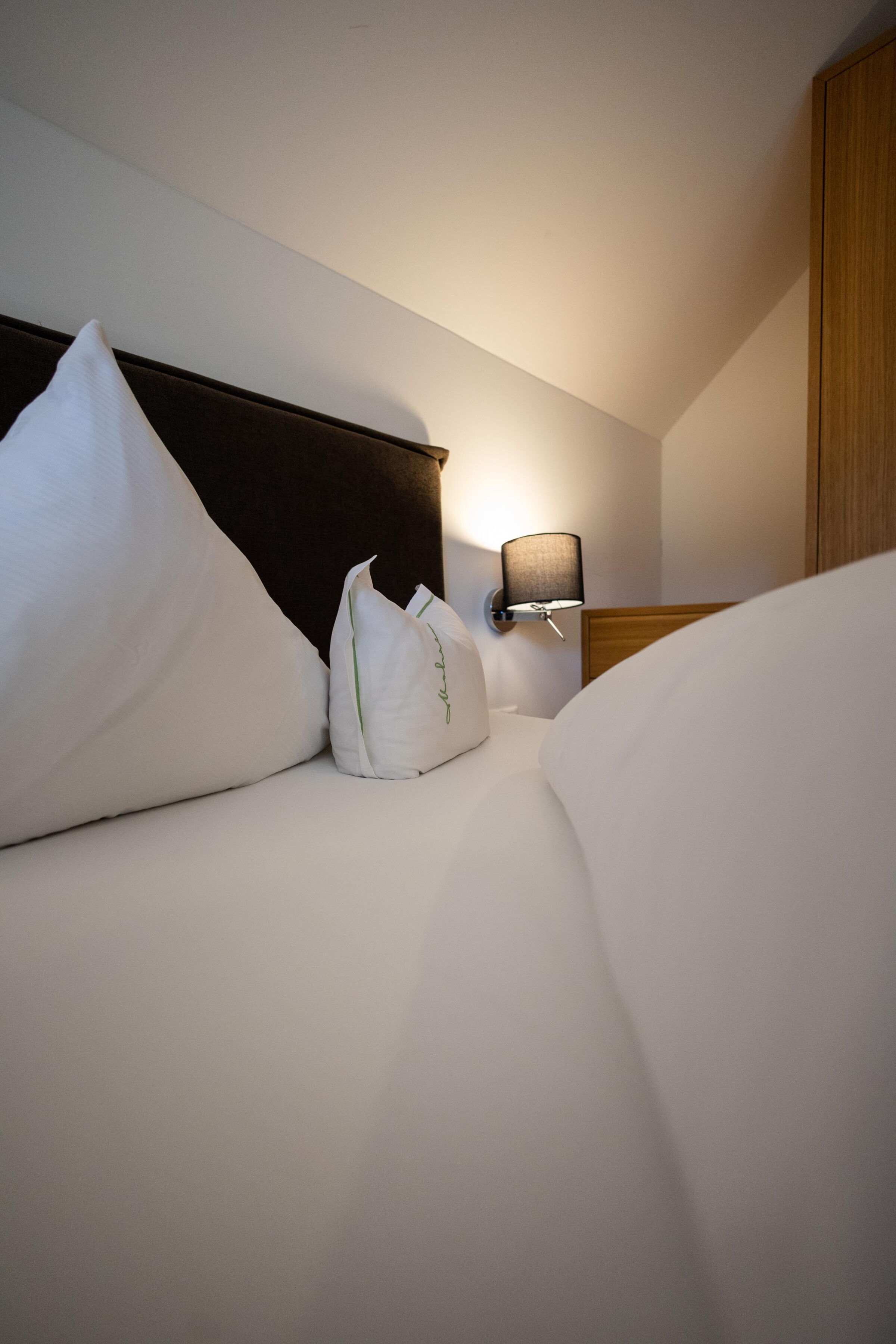 Soft double bed with elegant lighting and stylish headboard in a hotel room.