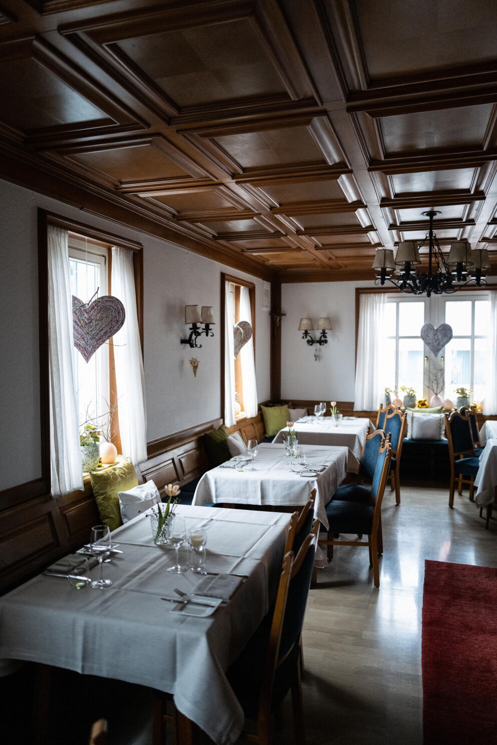 Elegant dining room with wooden elements, laid tables and warm decorations.
