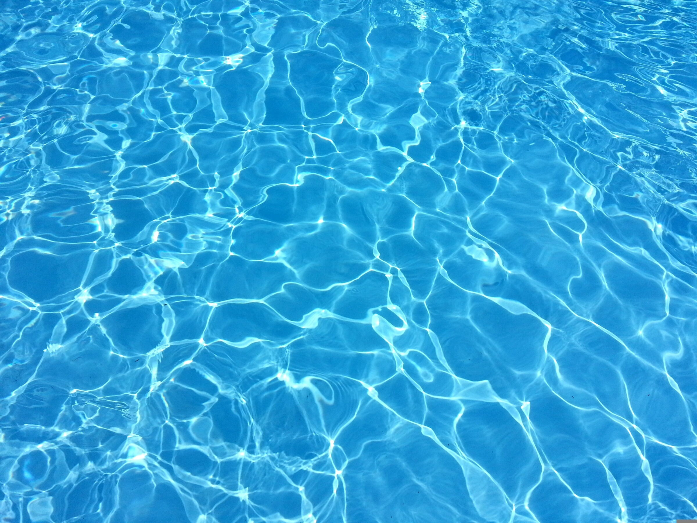 Blaues Wasser mit Sonnenreflexionen und sanften Wellenbewegungen.