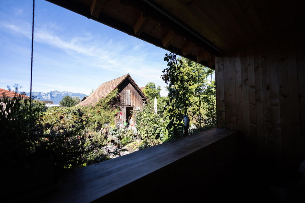 View of an idyllic garden with old wooden houses and mountain panorama.