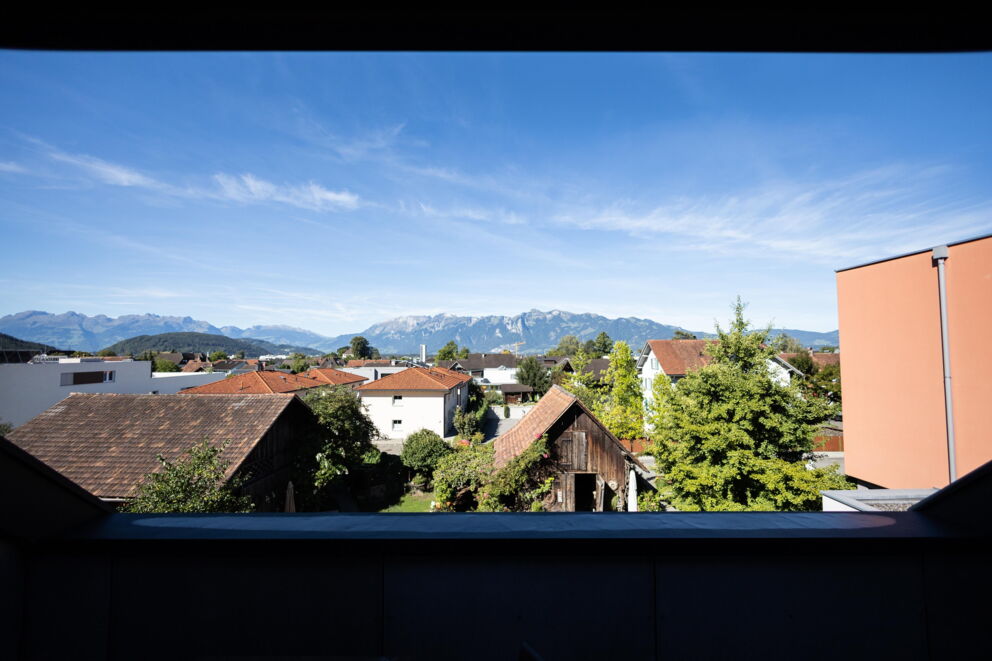 Sicht auf Dächer und Berge unter klarem, blauem Himmel in Vorarlberg.