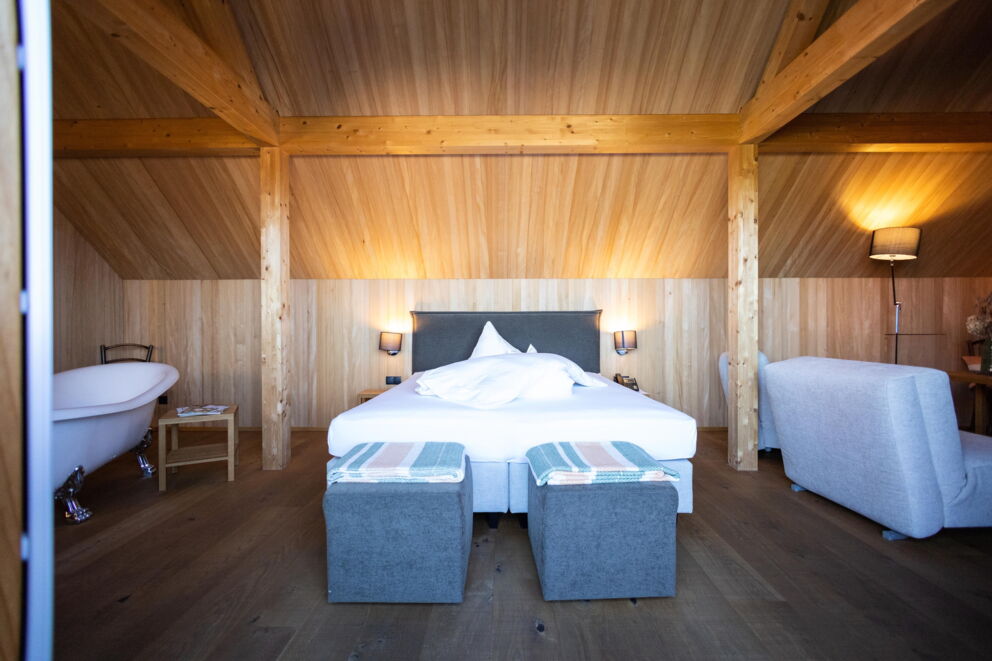 Holzkonstrukt mit gemütlichem Doppelbett, freistehender Badewanne und sanfter Beleuchtung.