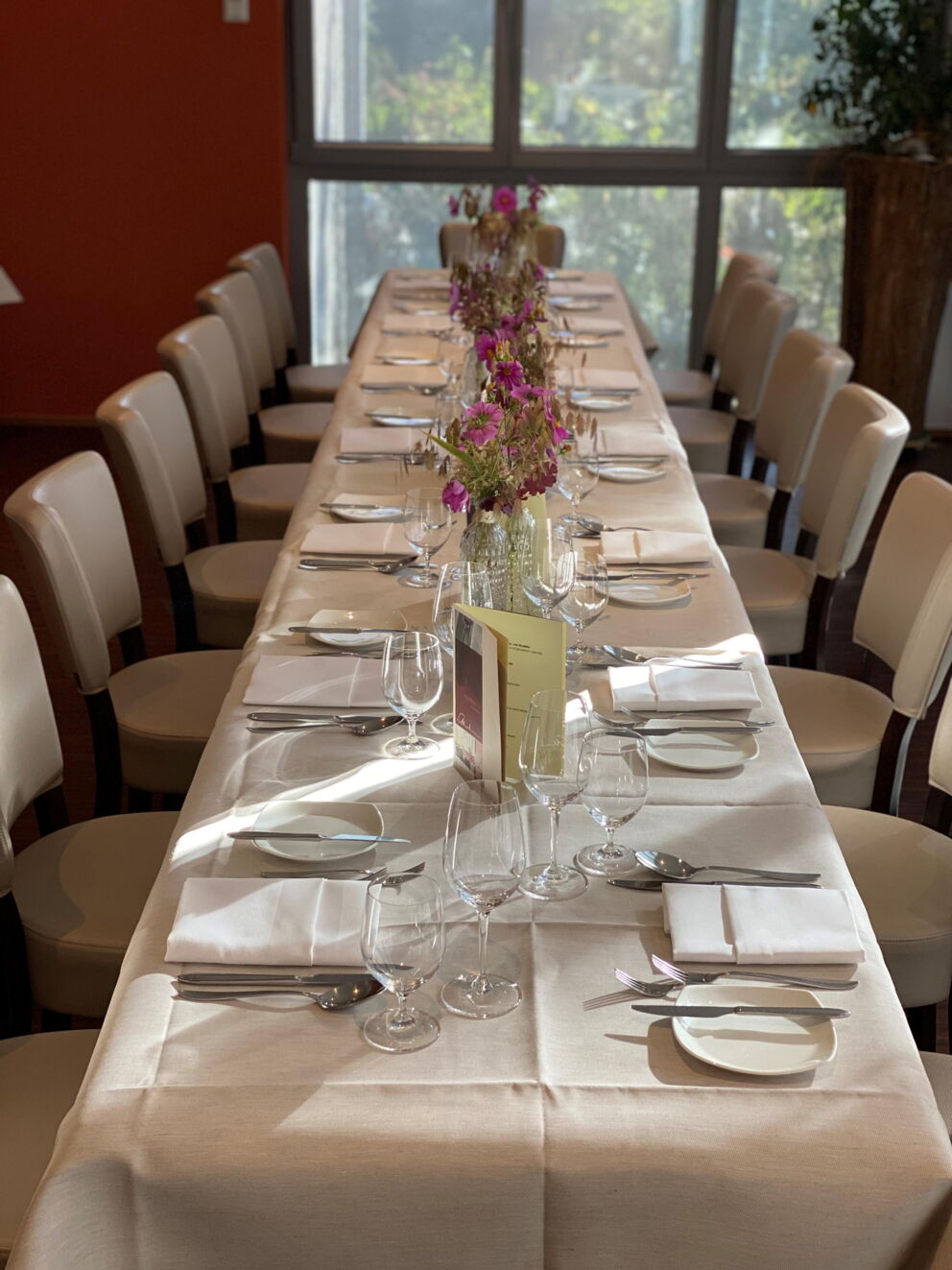 Long table with white tablecloths, delicate flowers and elegant place settings.