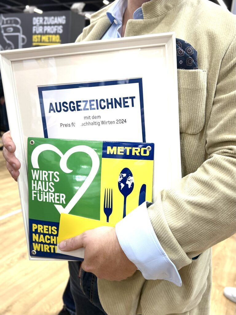 Person hält Auszeichnung für nachhaltiges Wirtschaften im Jahr 2024 in den Händen.