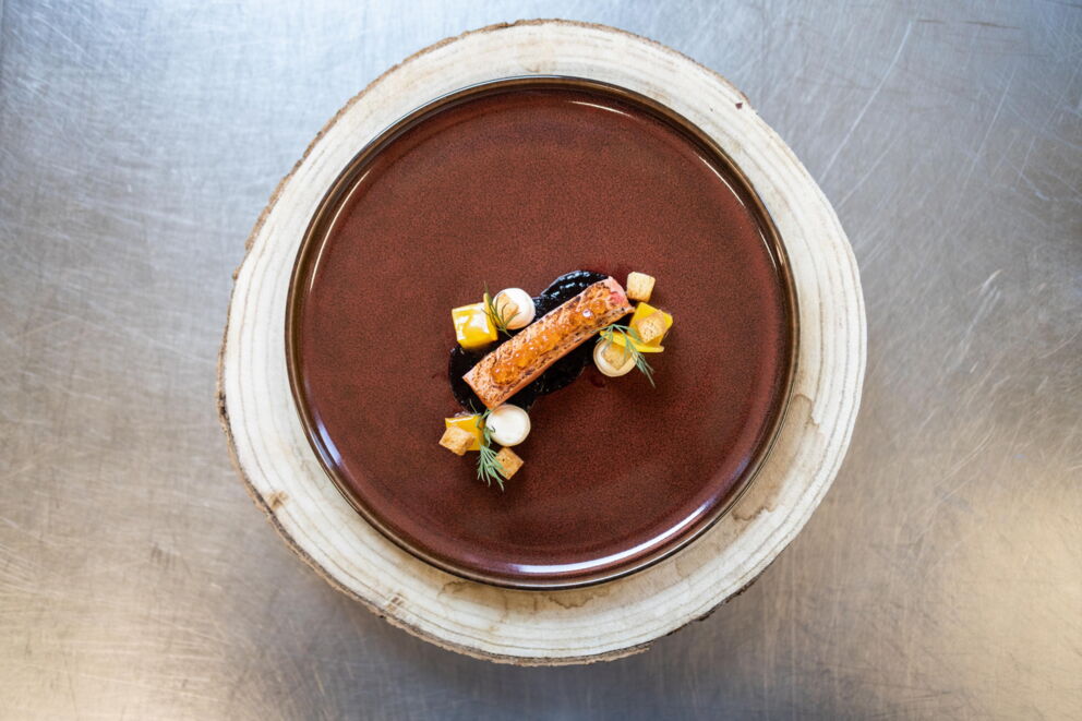 Elegant gourmet dish artfully presented on a brown plate with fine details.