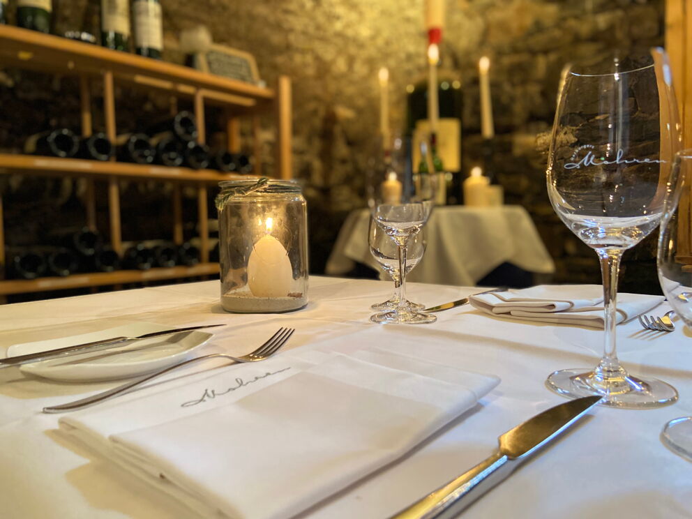 Elegant candlelit table surrounded by bottles of wine in the historic cellar.