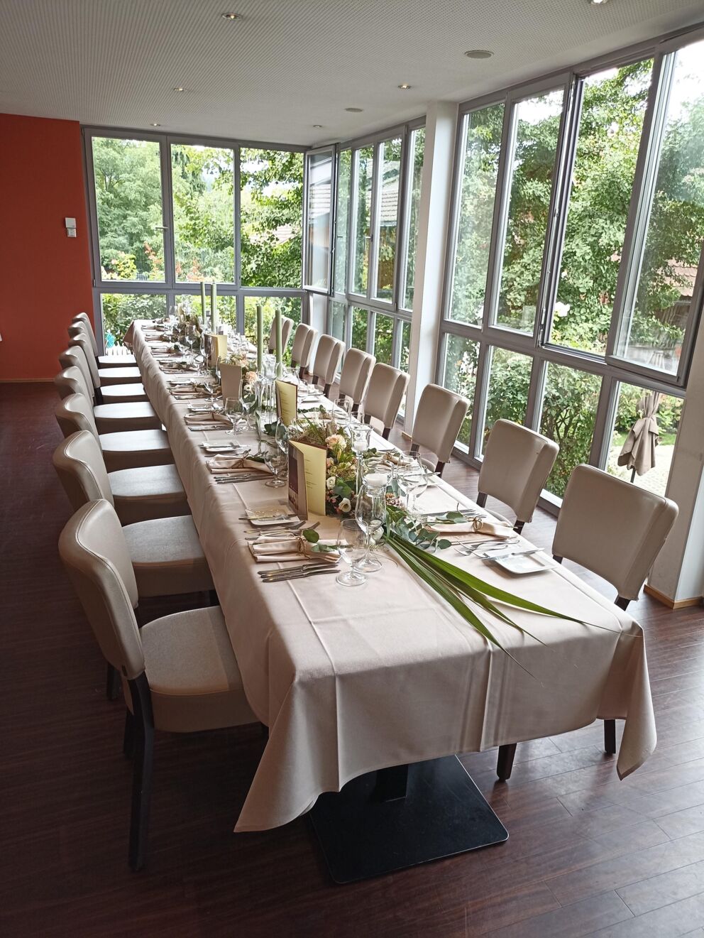 Long, elegantly laid table with a view of green trees in a bright room.