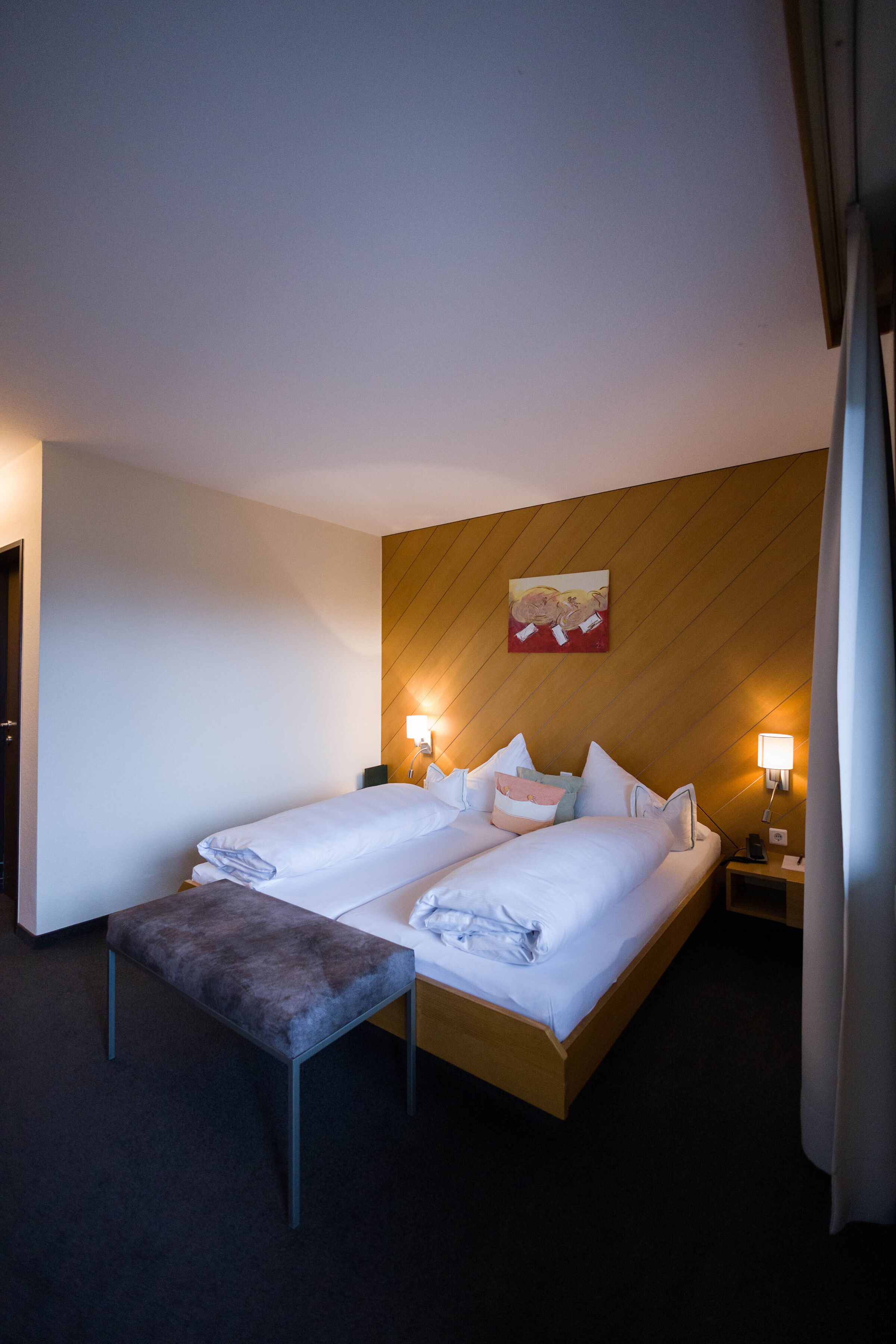 Cozy double room with wood paneling, soft bedding and soft lighting.