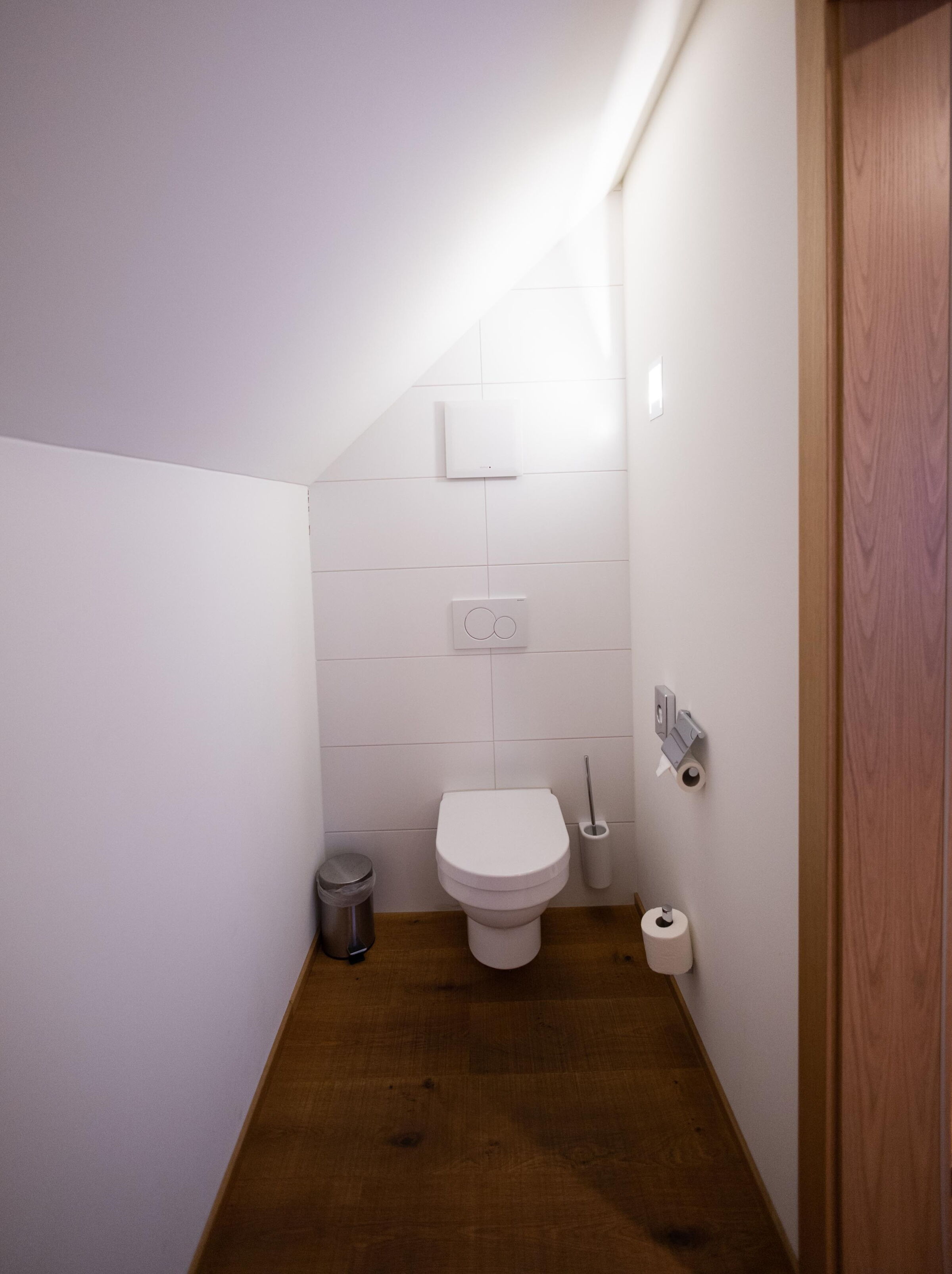 Elegant bathroom with wooden floor and minimalist white walls.