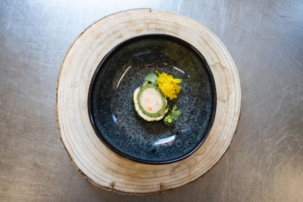Artfully arranged dish presented in a black bowl on a wooden disk.
