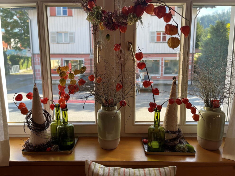 Windowsill with autumnal decorations and colorful dried flowers in vases.