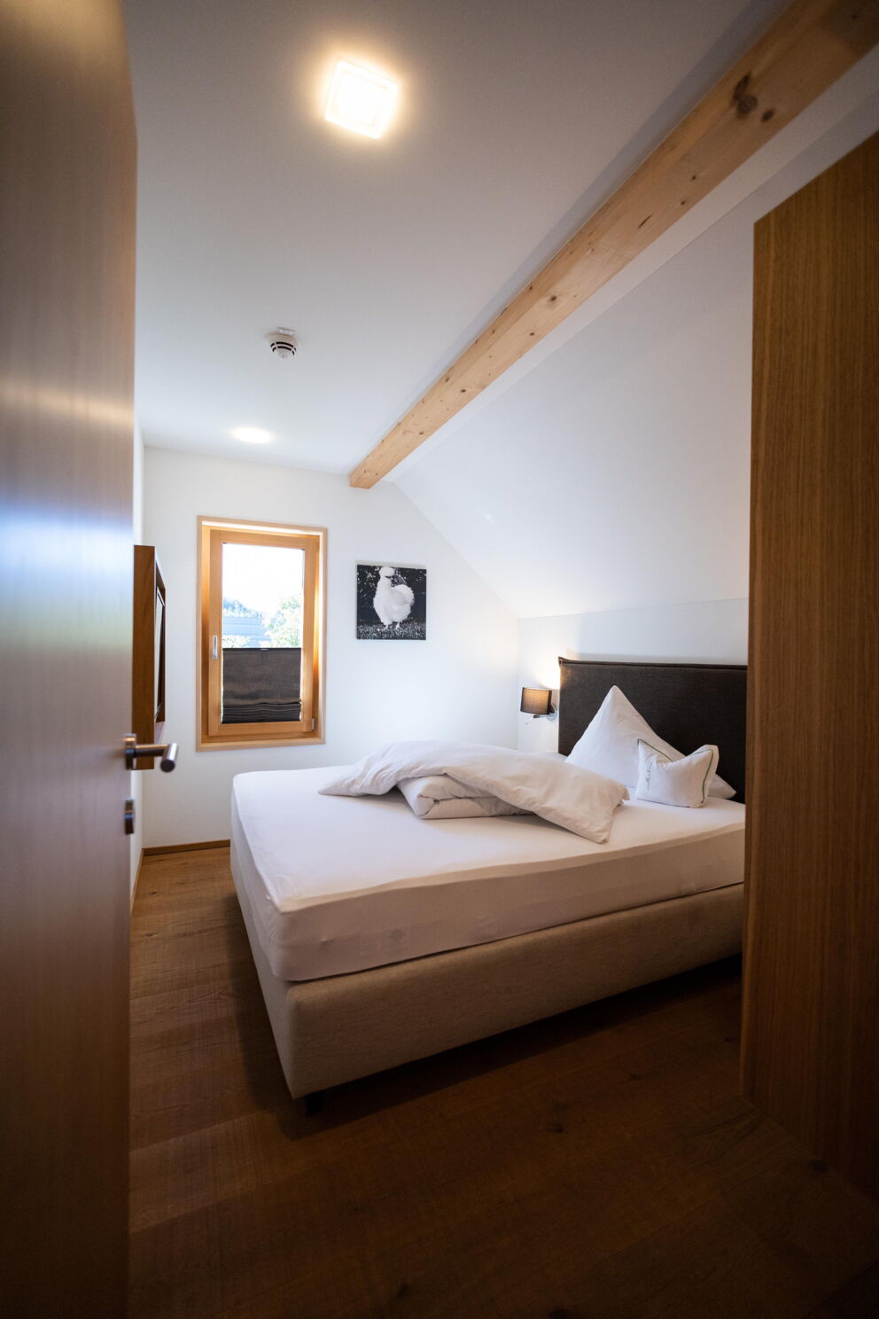 Helles Zimmer mit Holzelementen und komfortablem Bett für entspannte Nächte.