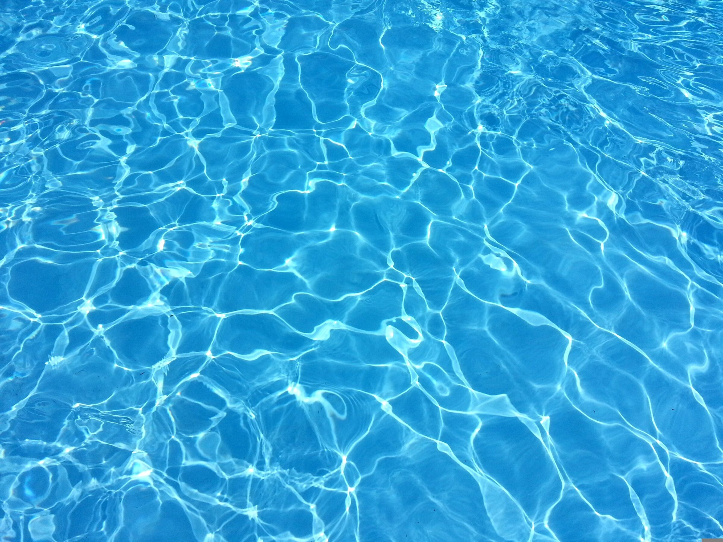 Blaues Wasser mit Sonnenreflexionen und sanften Wellenbewegungen.