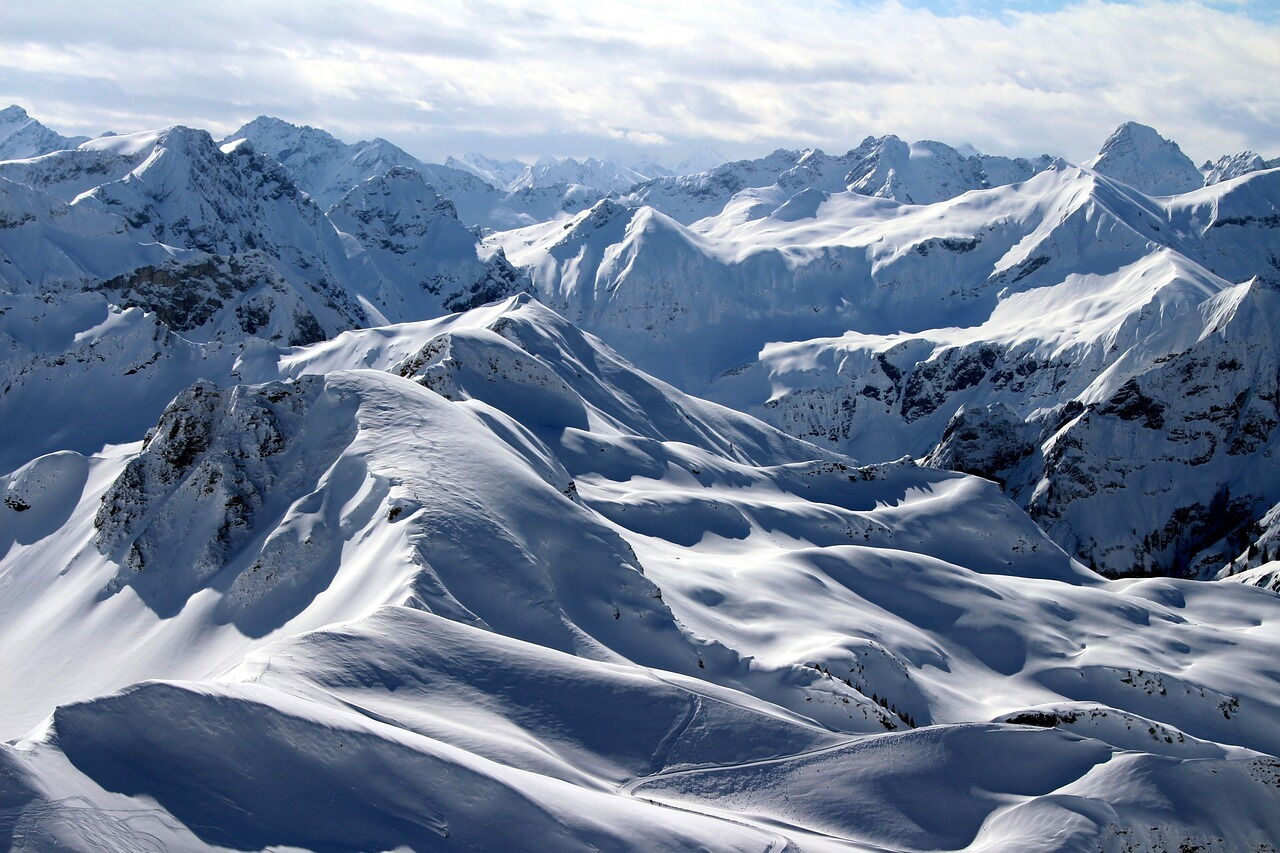 Majestätische verschneite Berge unter blauem Himmel, strahlende Winterlandschaft in den Alpen.