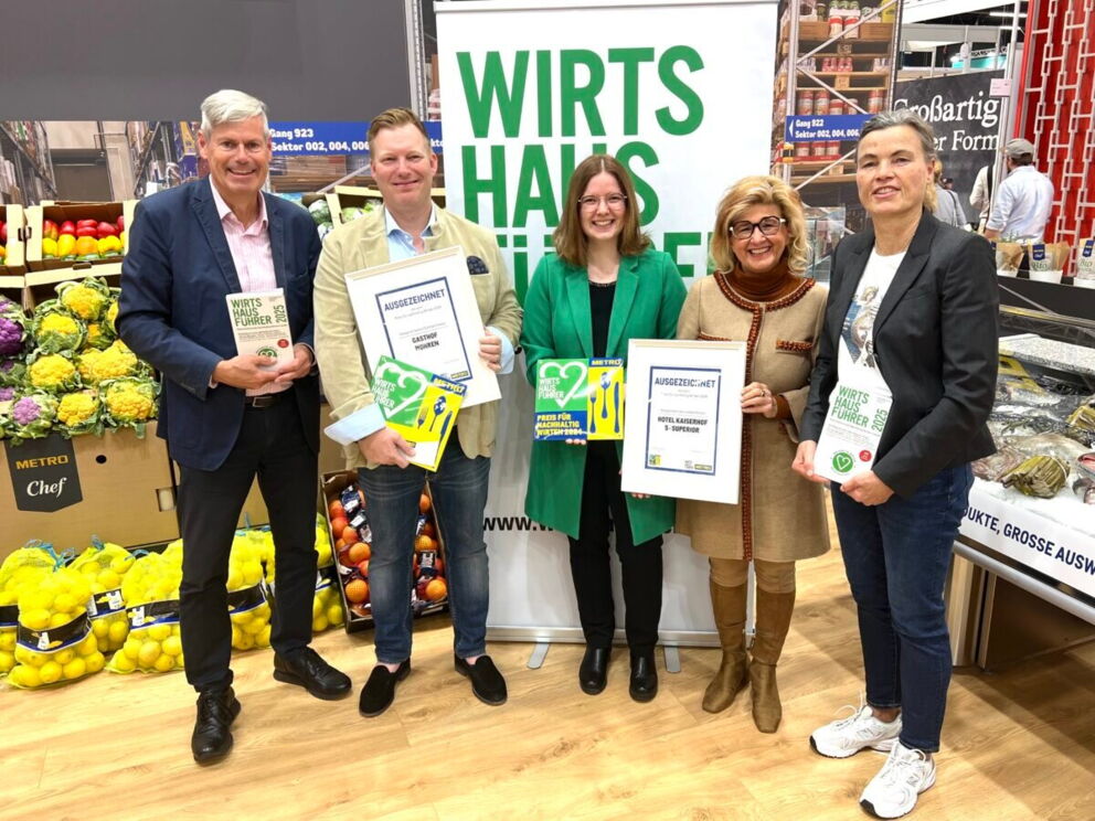 Gruppe von Menschen hält Zertifikate vor Obst- und Gemüsekisten