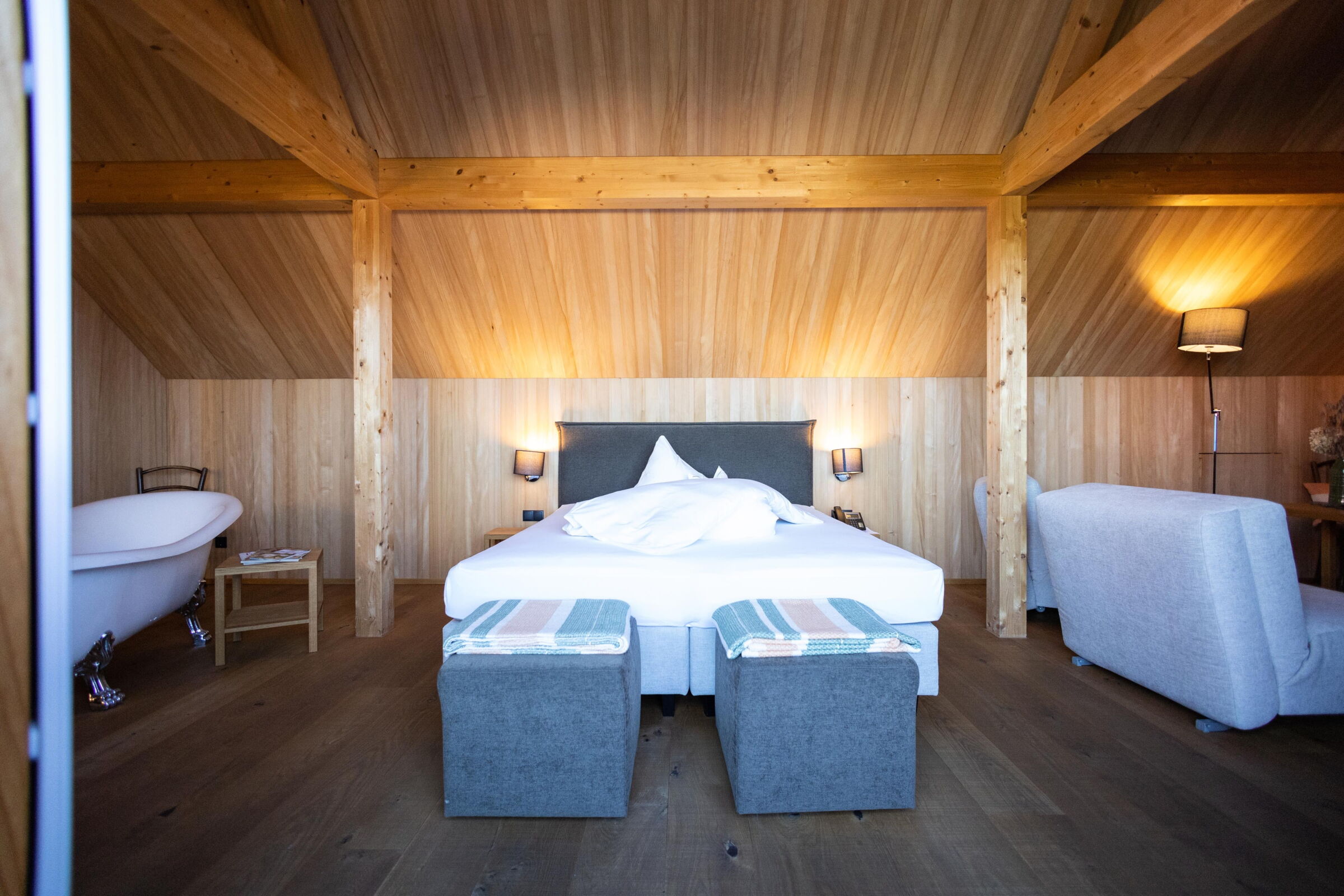 Wooden construction with cozy double bed, free-standing bathtub and soft lighting.