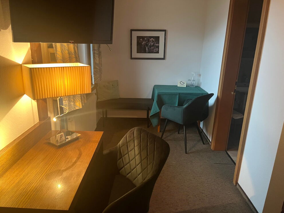 Moderne Einrichtung mit Schreibtisch, Sessel, Tisch, Lampe und Bild an der Wand.